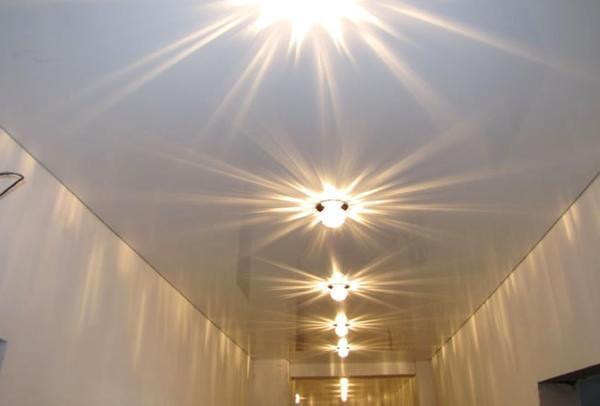 Установив красивые точечные светильники на белый потолок, можно добиться эффектного вида многократного отражения света на глянцевой поверхности полотна